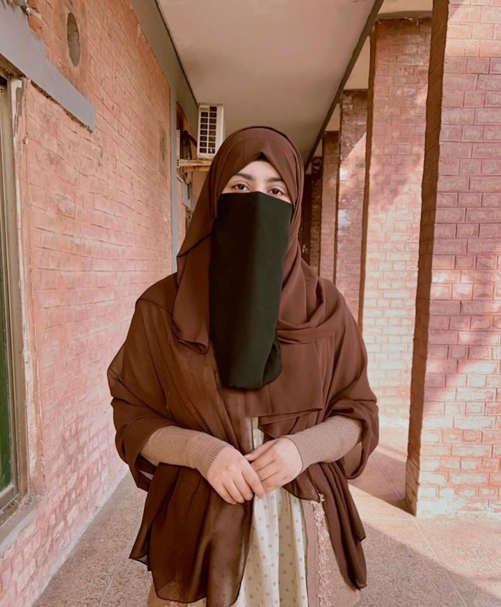 WRnUKmbz Kashmala Kiran in black niqab and brown hijab wearing abaya standing in corridor